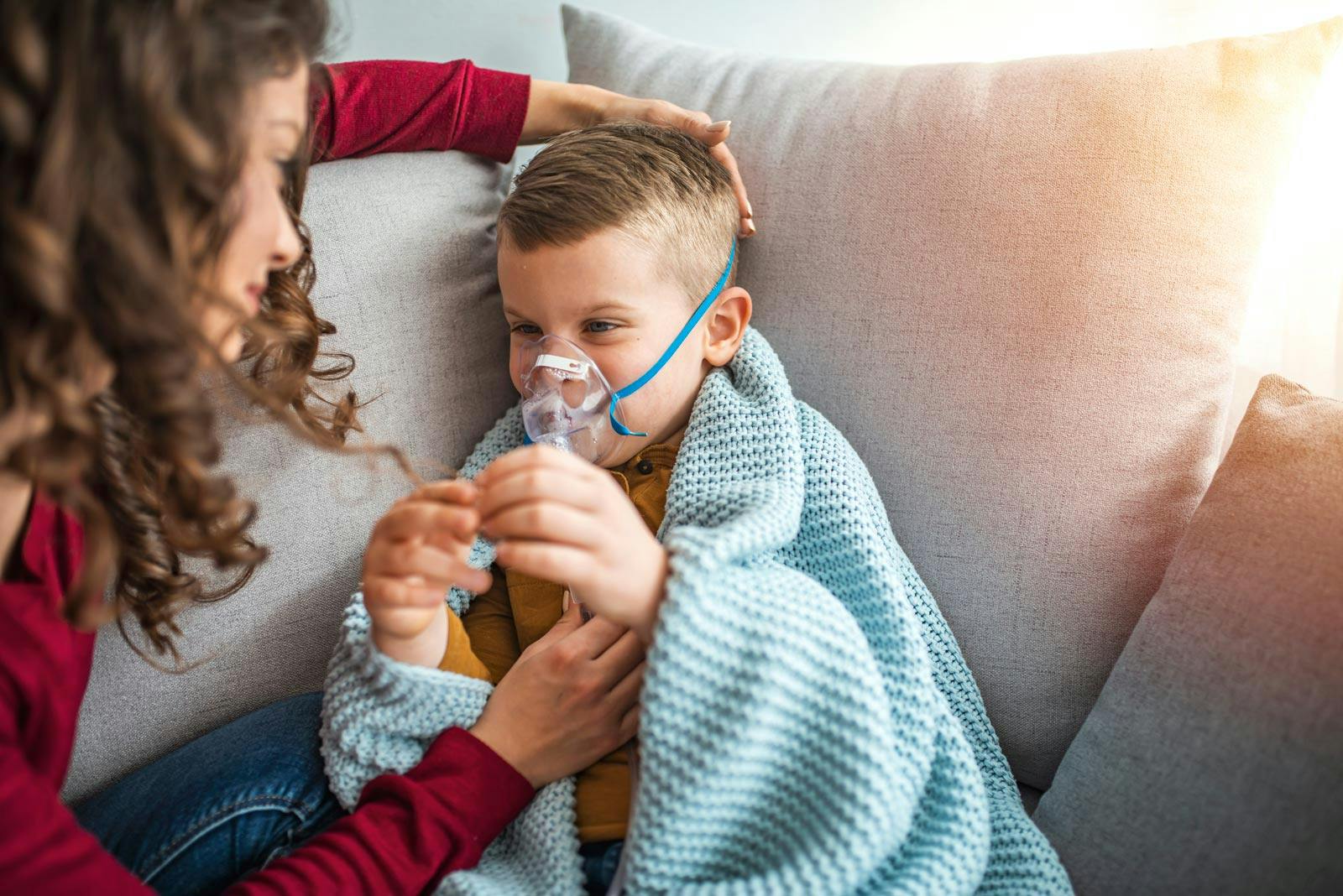 Mor hjelper gutt med innhalator